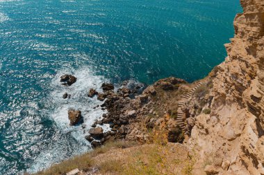 Kayalık kıyı manzarası ve dalgalı berrak mavi su. Doğa konsepti. Güzel yaz arkaplanı.