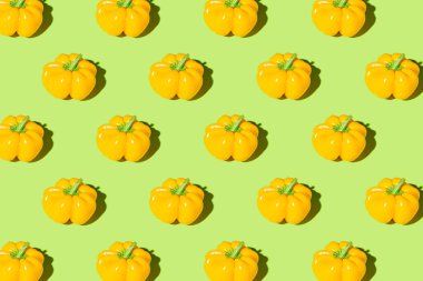 Creative pattern made of yellow bell pepper on green pastel background with shadows. Minimal style. Healthy food ingredient concept
