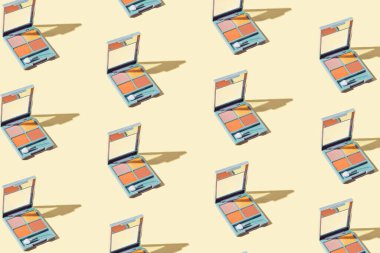 Pastel sarı arka planda göz farı paletlerinden oluşan yaratıcı desen. Güzellik ve makyaj konsepti. Asgari biçim.