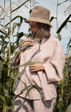 Güneşli bir yaz gününde keten takım elbiseli ve şapkalı genç bir kız mısır tarlasında duruyor. Seyahat ve macera aşkı.