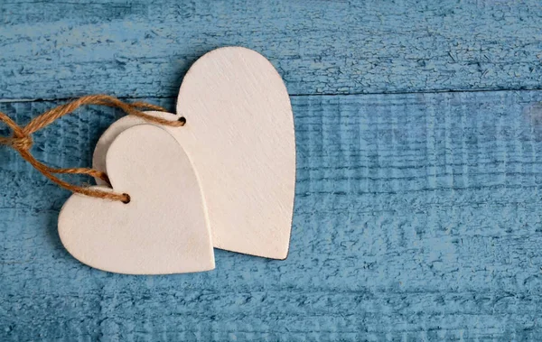 Happy Valentine`s Day greeting card.Holiday Valentine decoration.Two white wooden hearts on a blue background.Love or romantic concept Selective focus.