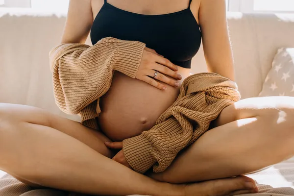 Крупный План Беременной Женщины Сидящей Диване Мягком Свете Обнимающей Живот — стоковое фото