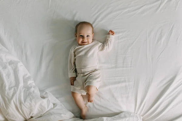 Bebê Vestido Com Roupas Brancas Deitado Lençol Branco Sorrindo Olhando — Fotografia de Stock