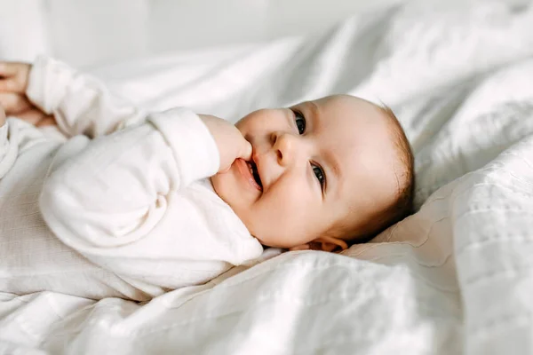 Szczęśliwe Dziecko Leżące Łóżku Uśmiechnięte Ssące Palce — Zdjęcie stockowe