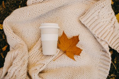 Beyaz örgü bir süveterin üzerinde, altın yapraklı, tekrar kullanılabilir beyaz kahve..
