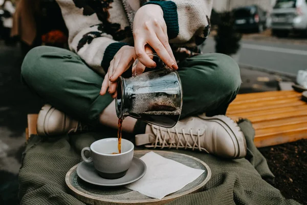 Bir kadının bardaktan bardağa sade kahve doldurduğu yakın plan..