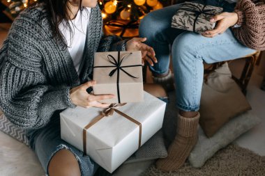 Noel ağacı arka planında paketlenmiş hediye kutularını tutan kadının yakın çekimi.