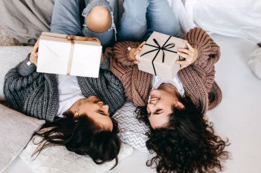 İki neşeli genç kadın ellerinde hediye paketleriyle, gülümsüyorlar..