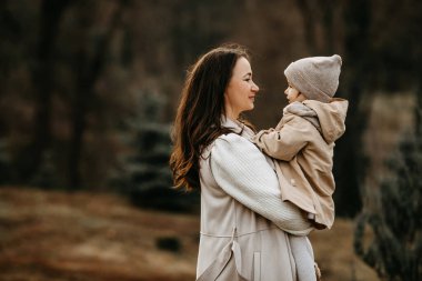 Anne küçük kızını bir sonbahar günü, dışarıda, bir parkta kollarına aldı..
