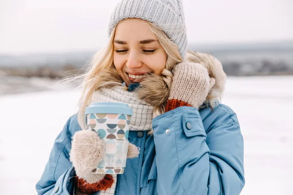 幸せな若いですブロンド女性を保持しています再利用可能なカップのコーヒー冬の日 — ストック写真