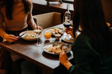 İki kadının bir kafede öğle yemeği yiyip, şarap içmesi..