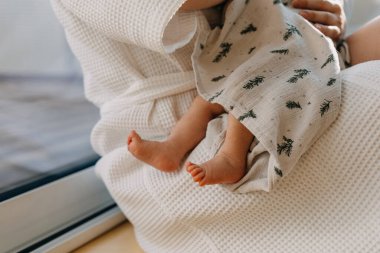 Yalınayak yeni doğmuş bebek ayaklarına yakın çekim. Anne kucağında küçük bir çocuk.