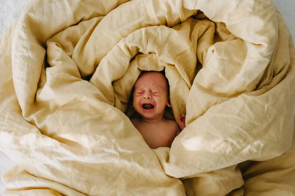 Νεογνό Μωρό Κλαίει Ξαπλωμένο Στο Κρεβάτι Καλυμμένο Μεγάλη Κίτρινη Κουβέρτα — Φωτογραφία Αρχείου
