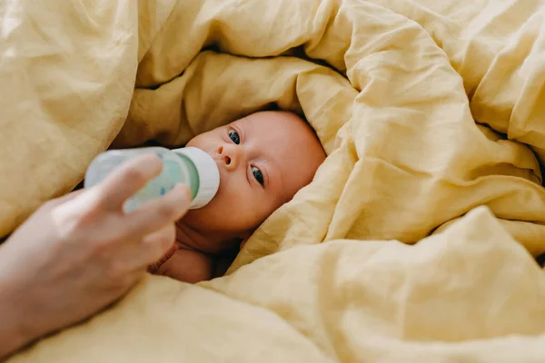 Бутылка Матери Кормит Новорожденного Ребенка Лежащего Постели Покрытая Большим Желтым — стоковое фото