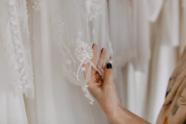 ウェディングドレスを見ている女性の閉鎖 手動で刺繍されたガウンスリーブに触れる ウェディングショールームで — ストック写真