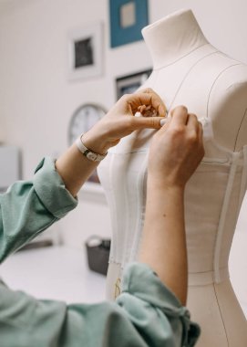 Atölyesinde bir terzinin çalışma süreci. Eller gelinlik dikme, mankene dantel takma.. 