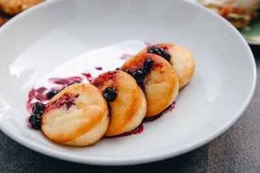 Ekşi kremalı ve beyaz tabakta reçelli süzme peynir krepleri..