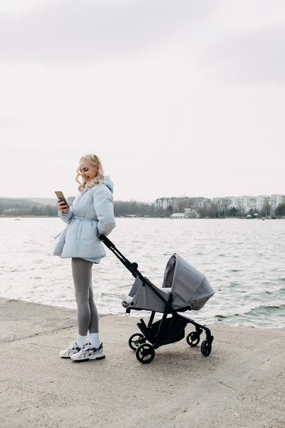 Woman Walking Stroller Lake Looking Her Smartphone — стоковое фото