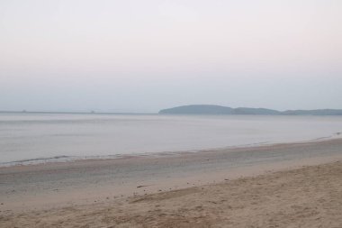 Gün doğmadan önce doğanın saflığı, ince kumda dalgalanan yumuşak deniz dalgaları.