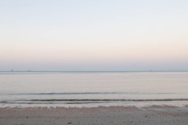 Güneş batmadan önceki sahilin manzarası, huzurlu ve sakin, deniz dalgaları ince kumu hafifçe vurur, rüzgarlı rüzgarla.