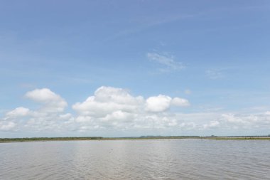 Tereyağlı mavi gökyüzü, süt bulutları ve güneşli bir günde huzurlu deniz.