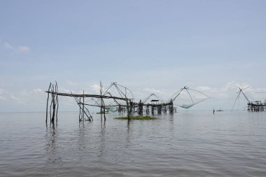 Güneşli bir günde mavi denizde ahşap bir yapı üzerine Dip Net Kare