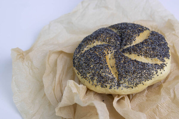 Poppy Seeds Kaiser Roll Wrapped with Brown Paper on White Background