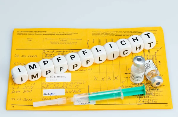 强制疫苗接种 带有疫苗和国际疫苗接种护照的注射器 用骰子写的疫苗 Impfen德语 意为强制接种 图库照片