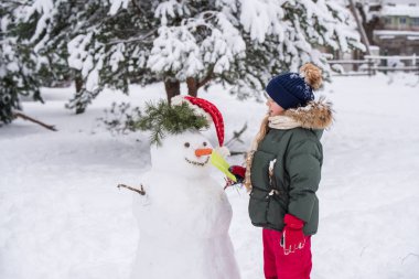 Mutlu sarışın şirin kız bir kardan adama mektup verir.