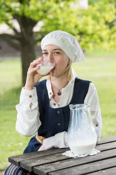 Latvian woman in traditional clothing with milk glass on nature — Stock Photo, Image