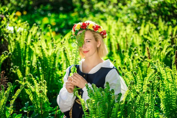 Νεαρή γυναίκα με εθνικά ρούχα και στεφάνι στο φόντο μιας πράσινης φτέρης. Λίγκο Λετονικές διακοπές — Φωτογραφία Αρχείου