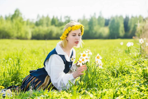 Junge Frau in Nationalkleidung auf einem Feld mit Narzissenblüten. — Stockfoto