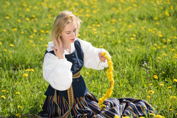 Молодая женщина в национальной одежде в желтом одуванчике на весеннем поле. Весна — стоковое фото
