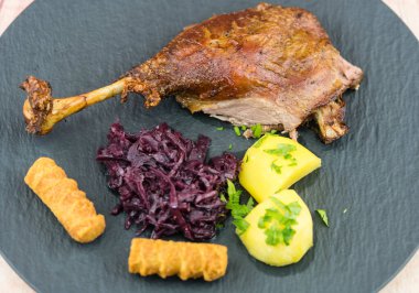 Kızarmış kaz ve patates, kırmızı lahana ve kahverengi sos.