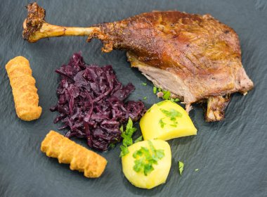 Kızarmış kaz ve patates, kırmızı lahana ve kahverengi sos.