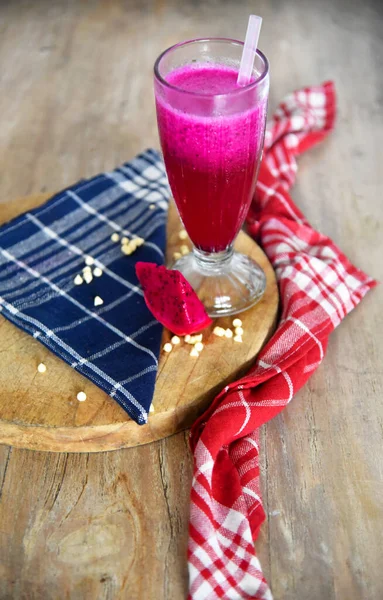 Kahverengi ahşap masaya ejderha meyvesi suyu konmuş.