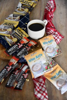 BALI, INDONEZYA-SEPTEMBER 09 2021: Ahşap masaya yerleştirilmiş bir çok boş kahve markasının ortasında bir fincan kahve, çoğunlukla Endonezya 'daki tatil beldelerinden alınmış gibi görünüyor. 