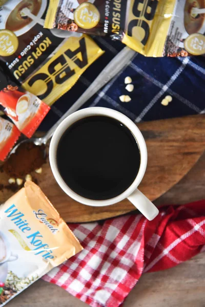 BALI, INDONEZYA-SEPTEMBER 09 2021: Ahşap masaya yerleştirilmiş bir çok boş kahve markasının ortasında bir fincan kahve, çoğunlukla Endonezya 'daki tatil beldelerinden alınmış gibi görünüyor. 