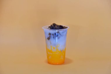 Plastik camda servis edilen taze süt ve çini soslu mango içeceği karışımı, iki katmanlı görünüş, arka planda izole edilmiş.