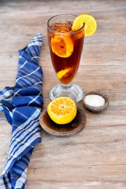 Kahverengi ahşap masaya konmuş turuncu buzlu çay.