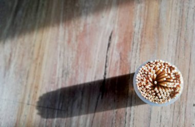 Kürdanlar ahşap masaya, güneş ışığı ve gölgeyle yerleştirilmiş.