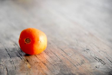 Kahverengi ahşap masaya yerleştirilmiş taze tek domates.