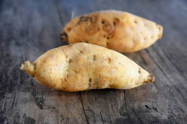 Kahverengi ahşap arka plana yerleştirilmiş iki tatlı patates.