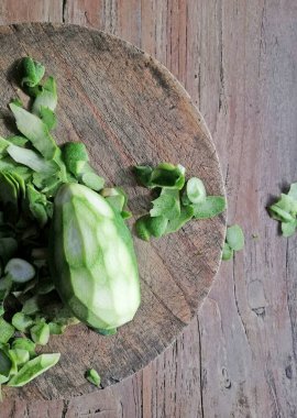 Açılmış, kesilmiş yeşil mango meyvesi, kahverengi ahşap arka plana yerleştirilmiş.