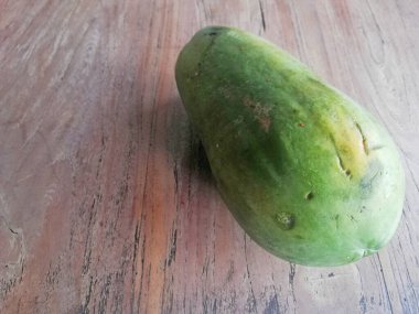 Kahverengi ahşap masaya yerleştirilmiş taze papaya meyvesi.