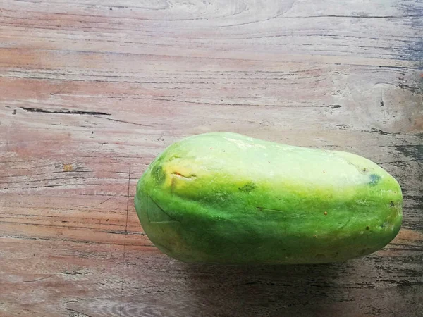 Kahverengi ahşap masaya yerleştirilmiş taze papaya meyvesi.