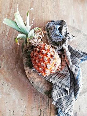 Kirli peçeteli sarı ananas, kahverengi ahşap arka planda.