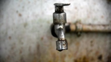 Üzerinde küçük su damlaları olan eski paslı musluk.