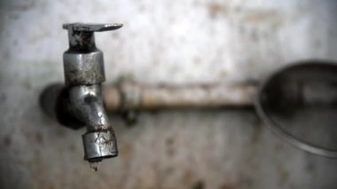 Üzerinde küçük su damlaları olan eski paslı musluk.