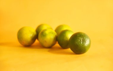 Turuncu meyve, sarı arka planda izole edilmiş.